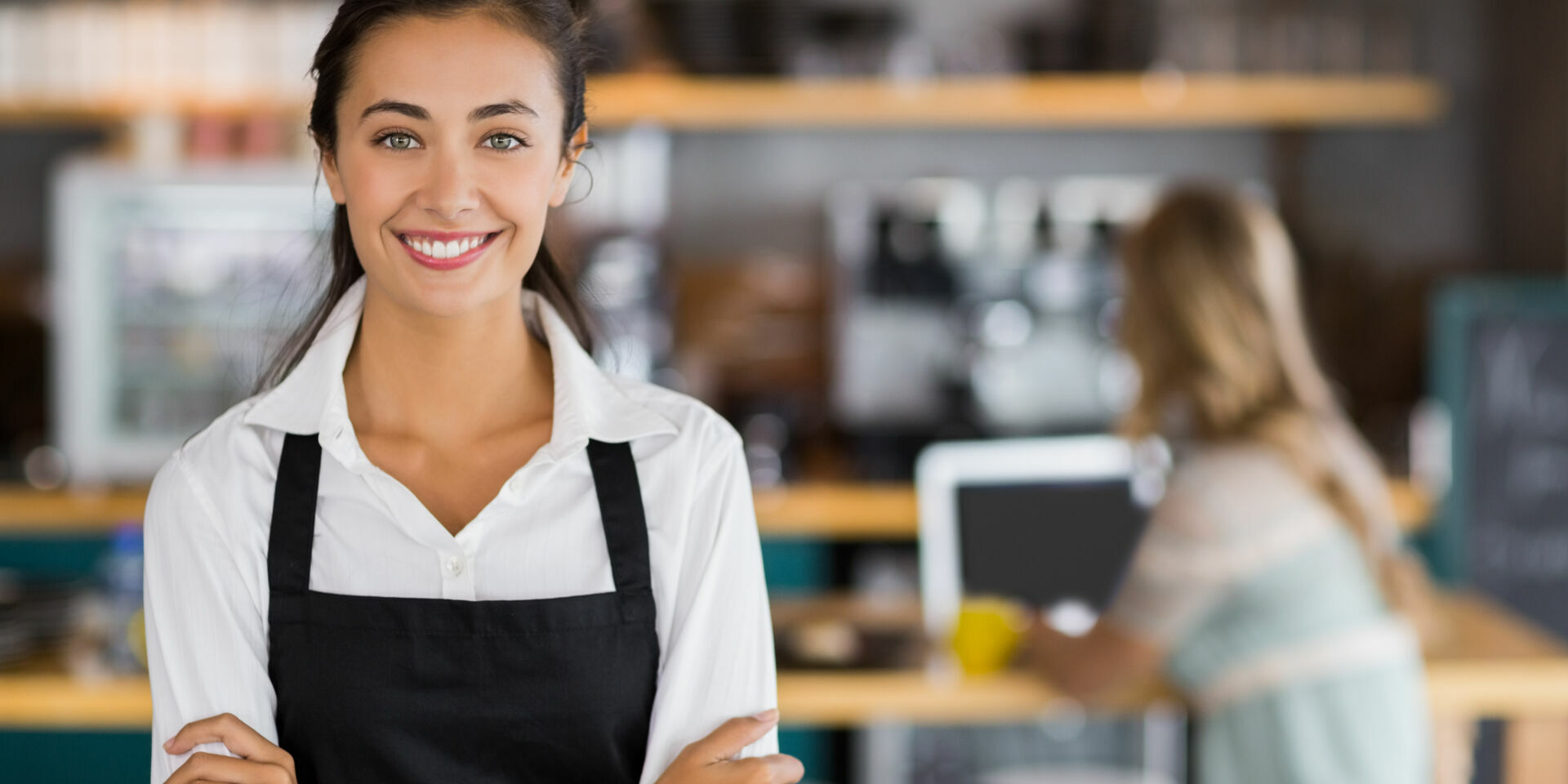 Portrait,Of,Smiling,Waitress,Standing,With,Arms,Crossed,In,Cafe